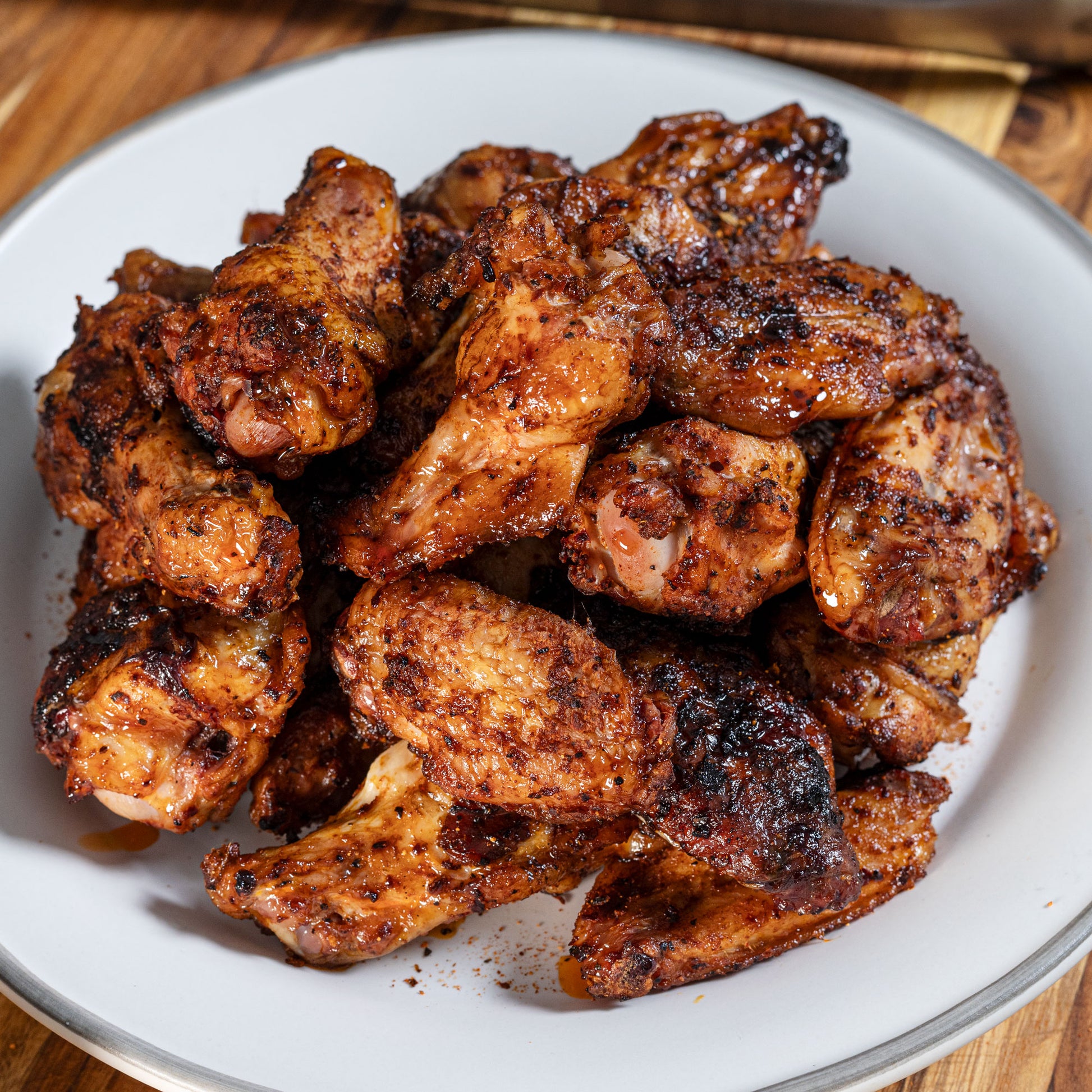 Grilled chicken wings coated in Chiles and Smoke BBQ rub on a white plate