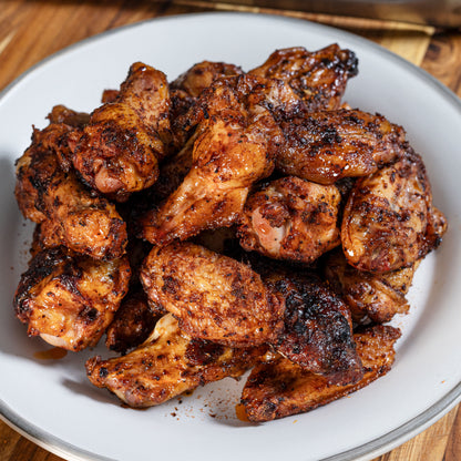 Grilled chicken wings coated in Chiles and Smoke BBQ rub on a white plate